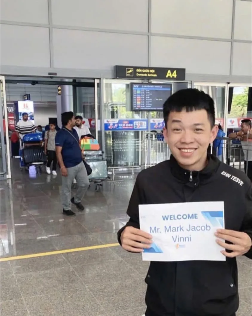 Xe Sân Bay Đà Nẵng Đi Hội An Giá Bao Nhiêu? So Sánh 2026 2 Tài xế Minh Vũ Travel cầm biển tên đón khách tại cửa Domestic Arrivals sân bay Đà Nẵng